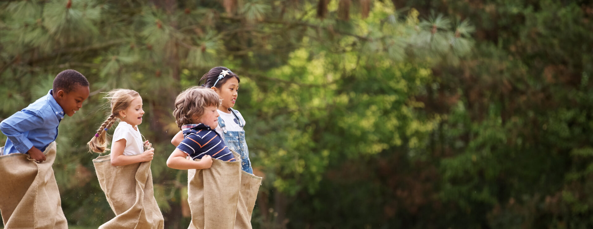 enfants faisant une course en sac sur un terrain d'herbe