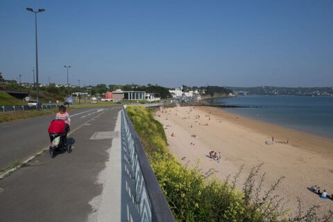 petite route qui surplombe la plage du moulin blanc. Ciel bleu et peu de monde sur la plage.
