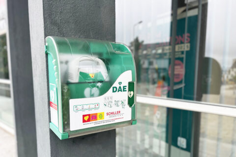défibrillateur en gros plan, sur une colonne grise à l'extérieur d'une mairie
