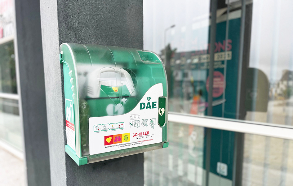 défibrillateur en gros plan, sur une colonne grise à l'extérieur d'une mairie