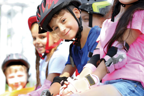groupe d'enfants habillés de couleurs vives et équipés d'un casque et de matériel de protection pour pratiquer le roller