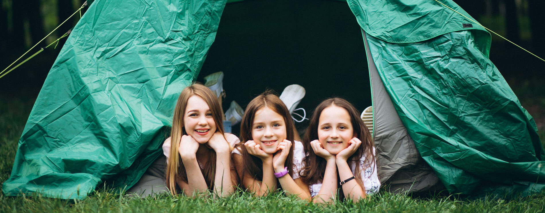 3 enfants dans une tente verte en pleine nature