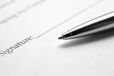 Stylo bille métal posé sur une feuille blanche sur laquelle est inscrit le "signature"