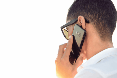 Homme de dos portant une chemise blanche, avec un téléphone portable à l'oreille