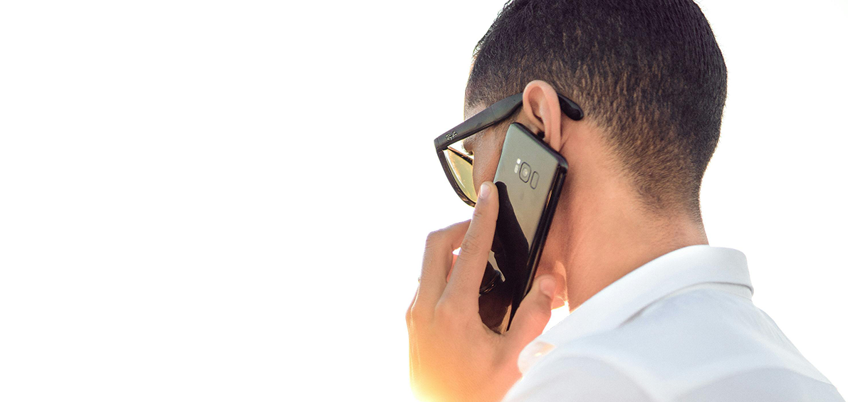 Homme de dos portant une chemise blanche, avec un téléphone portable à l'oreille