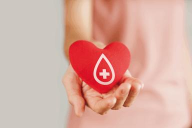 Une femme qui tend le bras. Un zoom est fait sur sa main, sur laquelle repose un coeur rouge. Sur ce coeur, la représentation d'une goutte de sang.