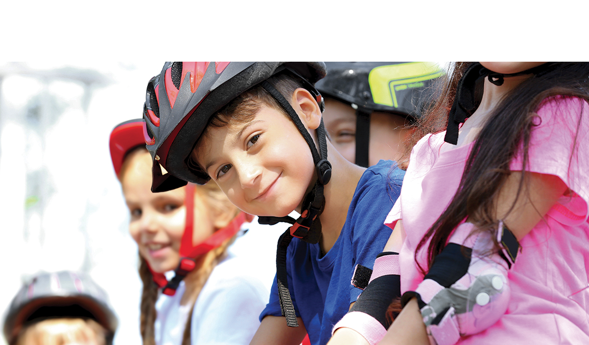 groupe d'enfants habillés de couleurs vives et équipés d'un casque et de matériel de protection pour pratiquer le roller