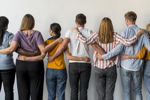 Jeunes hommes et femmes de dos qui se tiennent par les épaules.