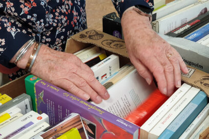 Mains de femmes fouillant dans une caisse de livres de poche. - Agrandir l'image, fenêtre modale