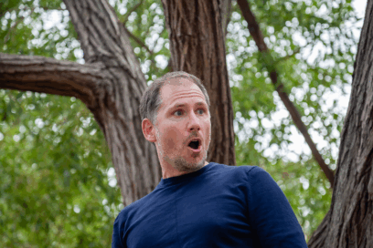 homme checeux châtain dans un bois. Il semble chanté ou être très surpris par quelque chose. - Agrandir l'image, fenêtre modale