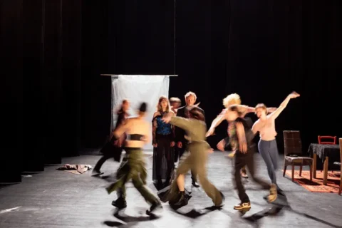 Photo illustrant le Conservatoire de Brest. Une salle plongée dans l'obscurité et des danseurs sur scène. Il s'agit sans doute de danse contemporaine.