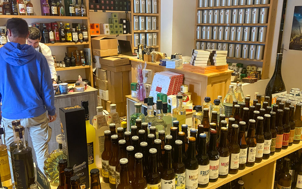 Intérieur de La Cave du coin où l'on voit des bouteilles mais aussi des pots de thé et des boites de chocolats - Agrandir l'image, fenêtre modale