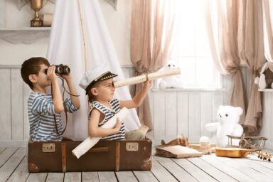 dans une chambre, des enfants dans une valise qui regardent au loin à travers des jumelles et une longue vue