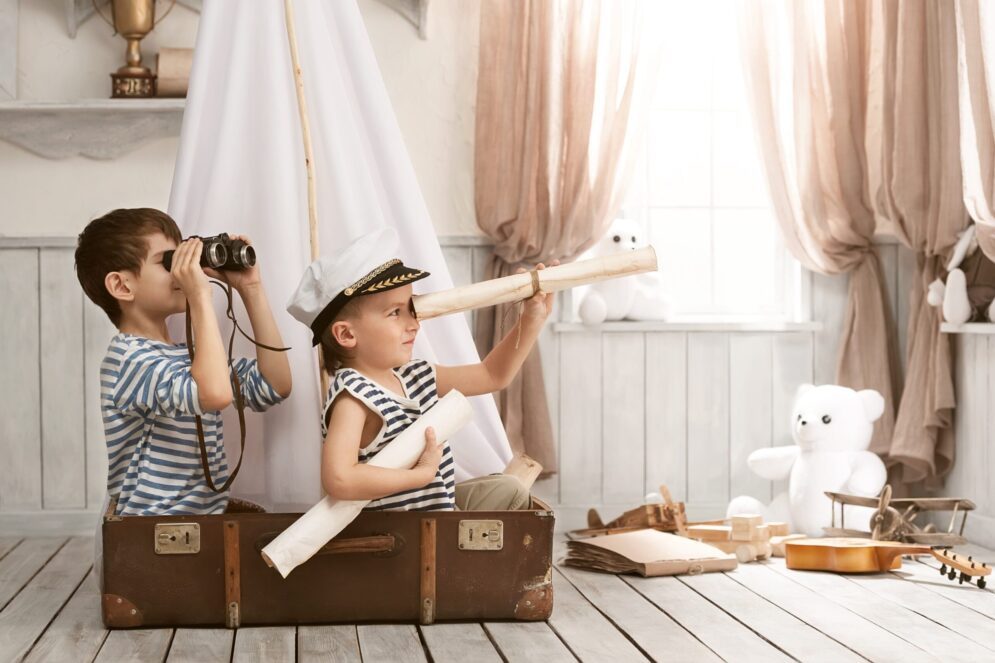 dans une chambre, des enfants dans une valise qui regardent au loin à travers des jumelles et une longue vue