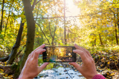 Les mains d'une personne tiennent un smartphone en mode photo et shootent la nature environnante - Agrandir l'image, fenêtre modale