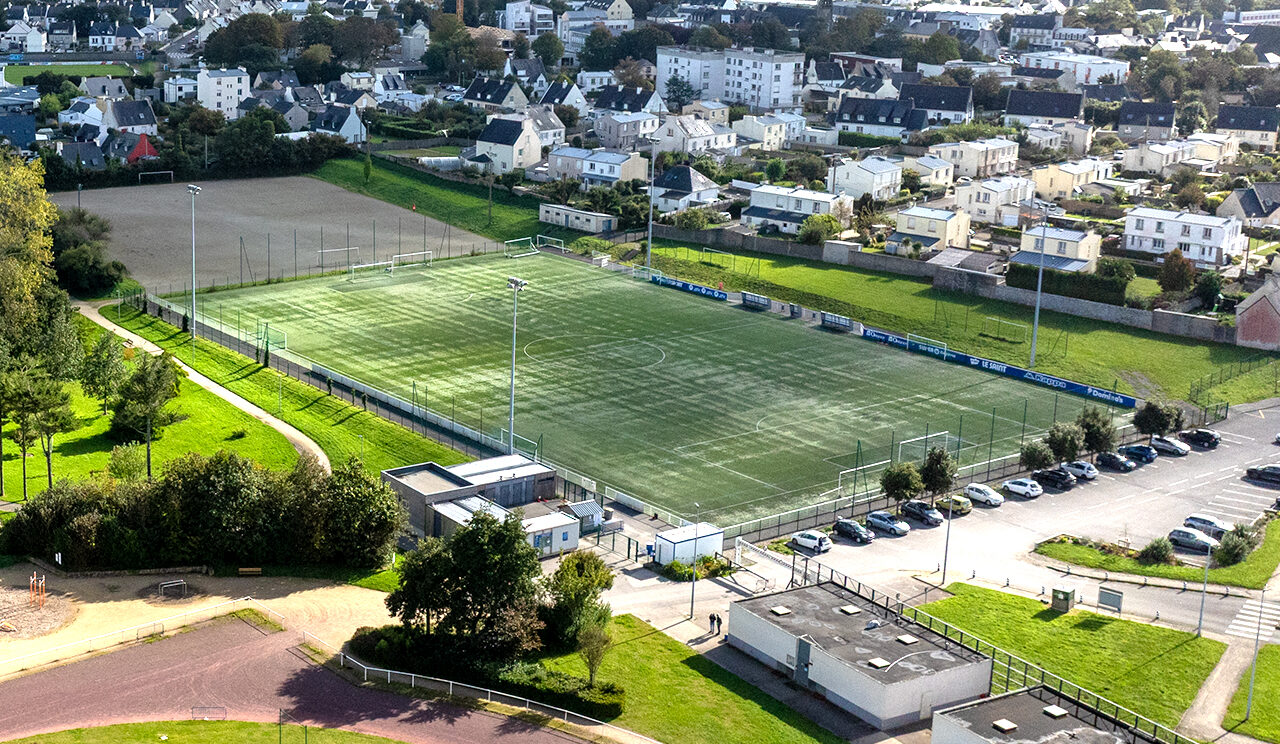 Vue aérienne par drone qui permet de distinguer les vestiaires et le terrain synthétique à Pontanné. Dazns le fond à gauche on aperçoit le terrain en stabilisé.