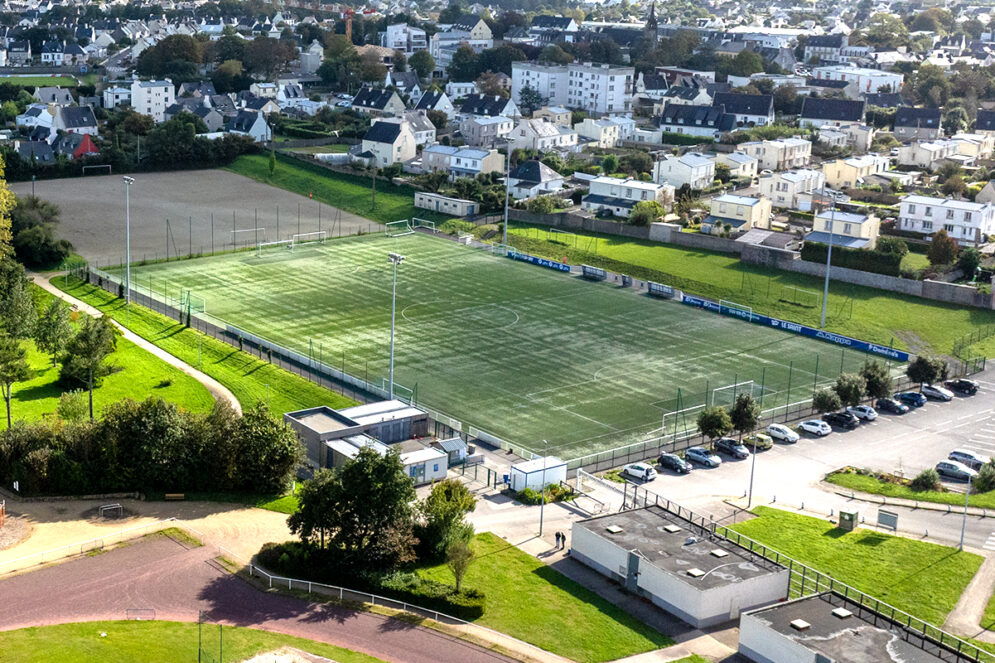 Vue aérienne par drone qui permet de distinguer les vestiaires et le terrain synthétique à Pontanné. Dazns le fond à gauche on aperçoit le terrain en stabilisé.