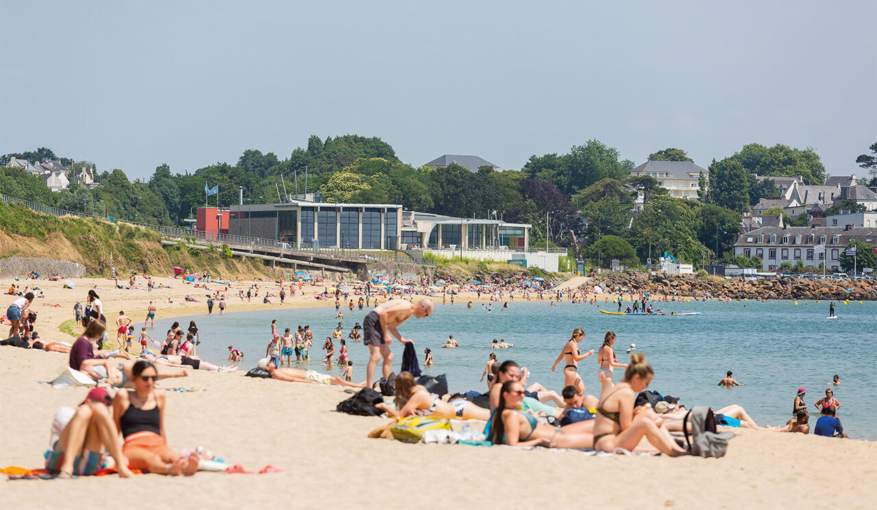 Vue d'estivants sur la plage du moulin Blanc. Certains sont sur leurs serviettes, d'autres se baignent