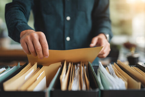 Des mains d'homme qui compulse un dossier papier