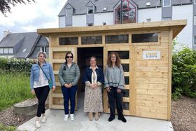 La porteuse de projet, l'élue au budget participatif et deux bénévoles posent devant la cabane à dons en bois installée dans le jardin de la Maison des solidarités